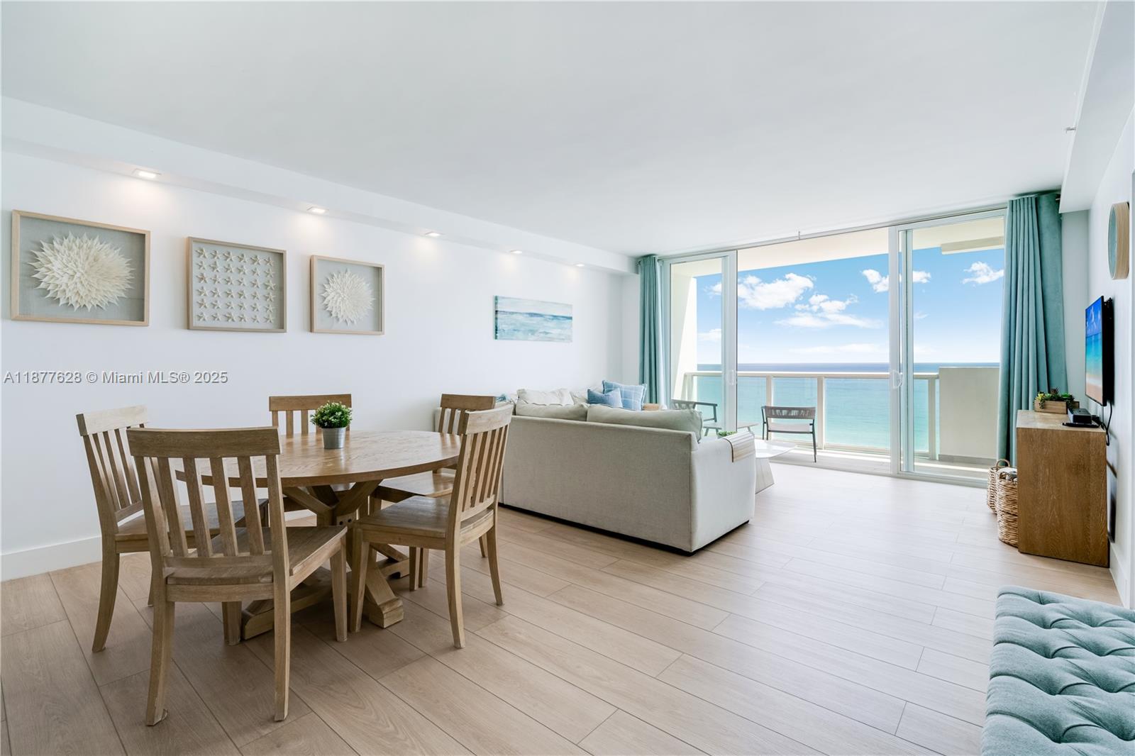 A bright living and dining area features light wood floors and a balcony overlooking ocean — 5601 Collins Ave # 1011, Miami Beach FL 33140, MIAMI BEACH, FL