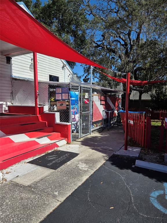 An exterior view shows a building entrance with red stairs, a shade canopy, and fencing — 528 E TARPON AVENUE, TARPON SPRINGS, FL
