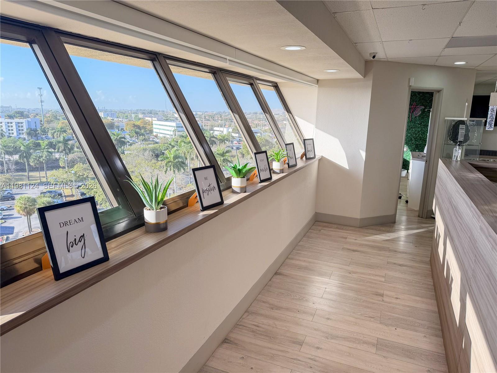 An office hallway features a long window ledge with potted plants and framed motivational signs — 7100 W 20th Ave # 616, Hialeah FL 33016, HIALEAH, FL
