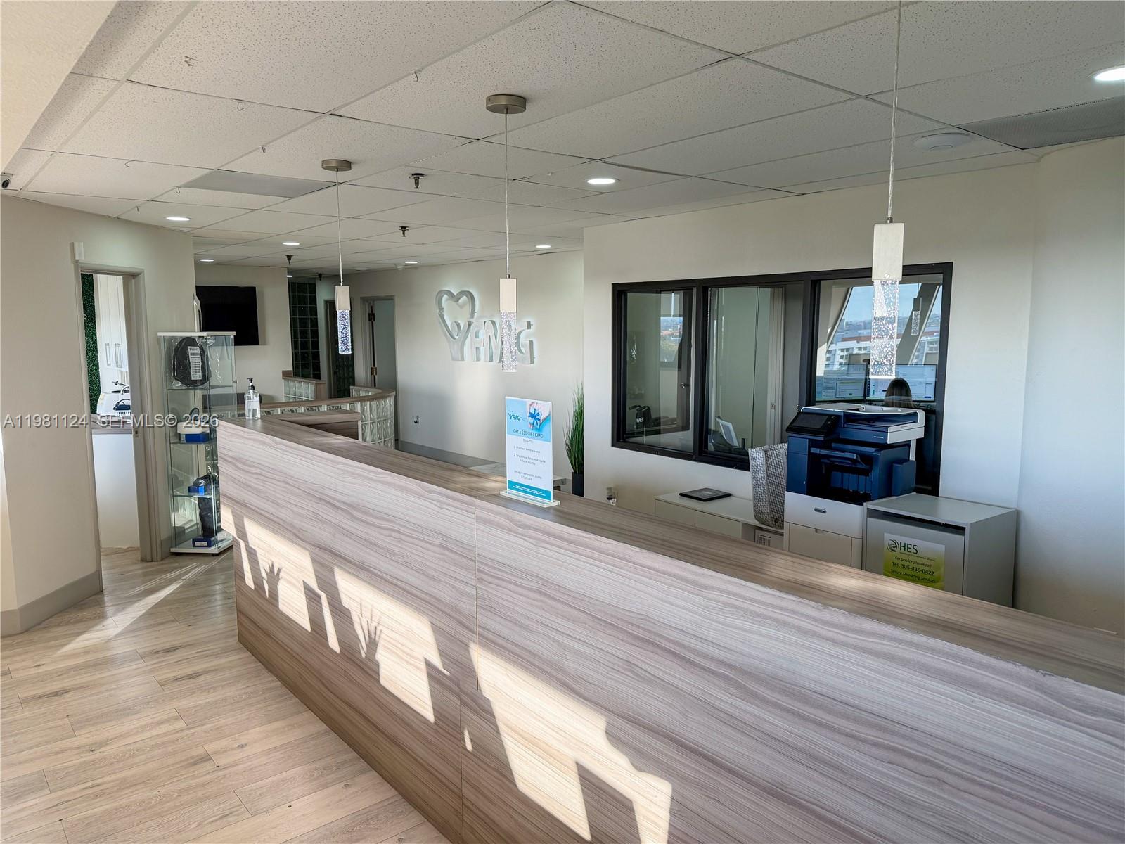 A reception area features a wood-grain desk, pendant lighting, and a glass-enclosed office space — 7100 W 20th Ave # 616, Hialeah FL 33016, HIALEAH, FL