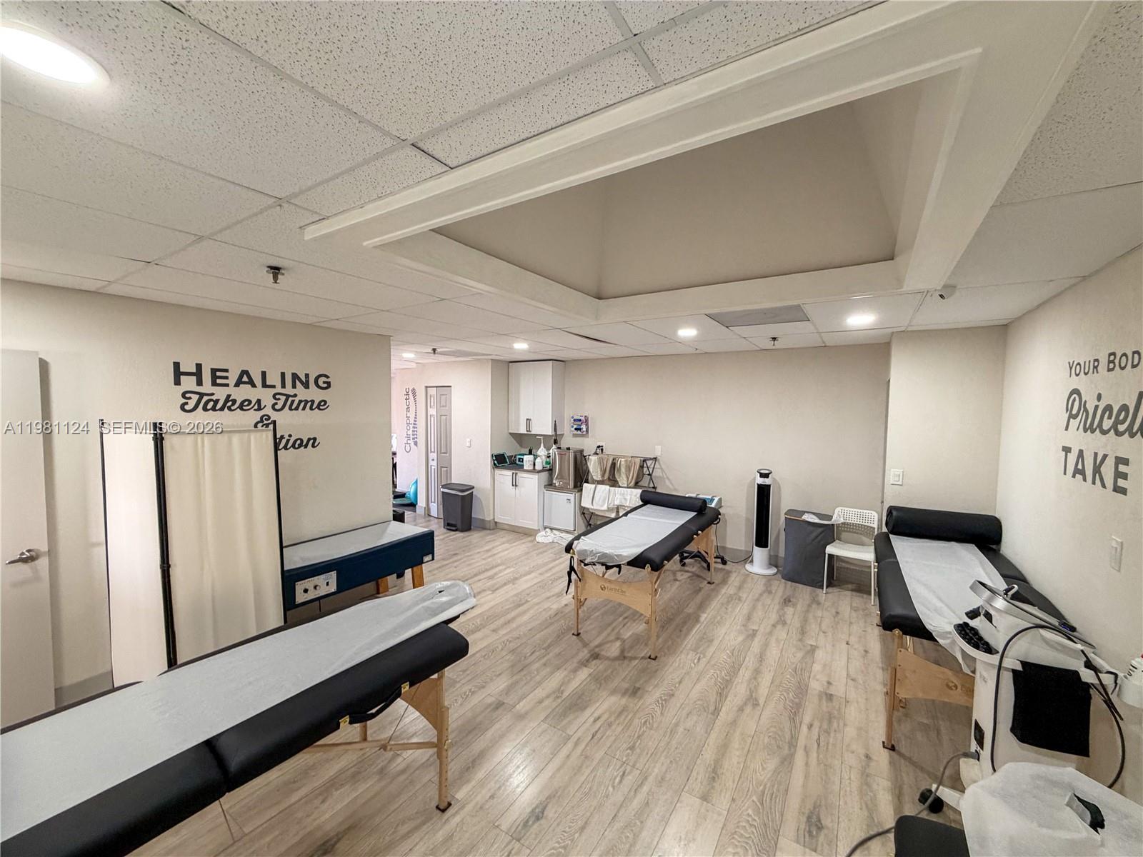 A treatment room features three massage tables, light wood flooring, and motivational wall text — 7100 W 20th Ave # 616, Hialeah FL 33016, HIALEAH, FL