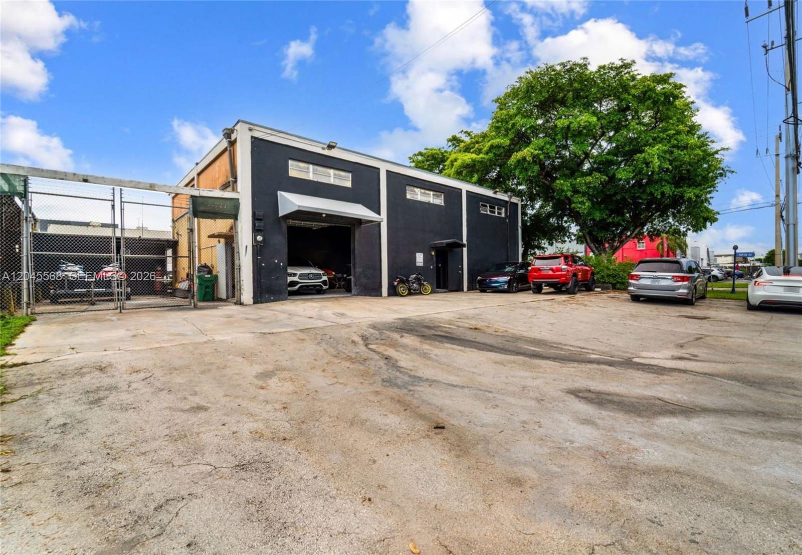 A black industrial building with a large garage bay and an adjacent parking lot — 5571 NW 84th Ave, Doral FL 33166, DORAL, FL