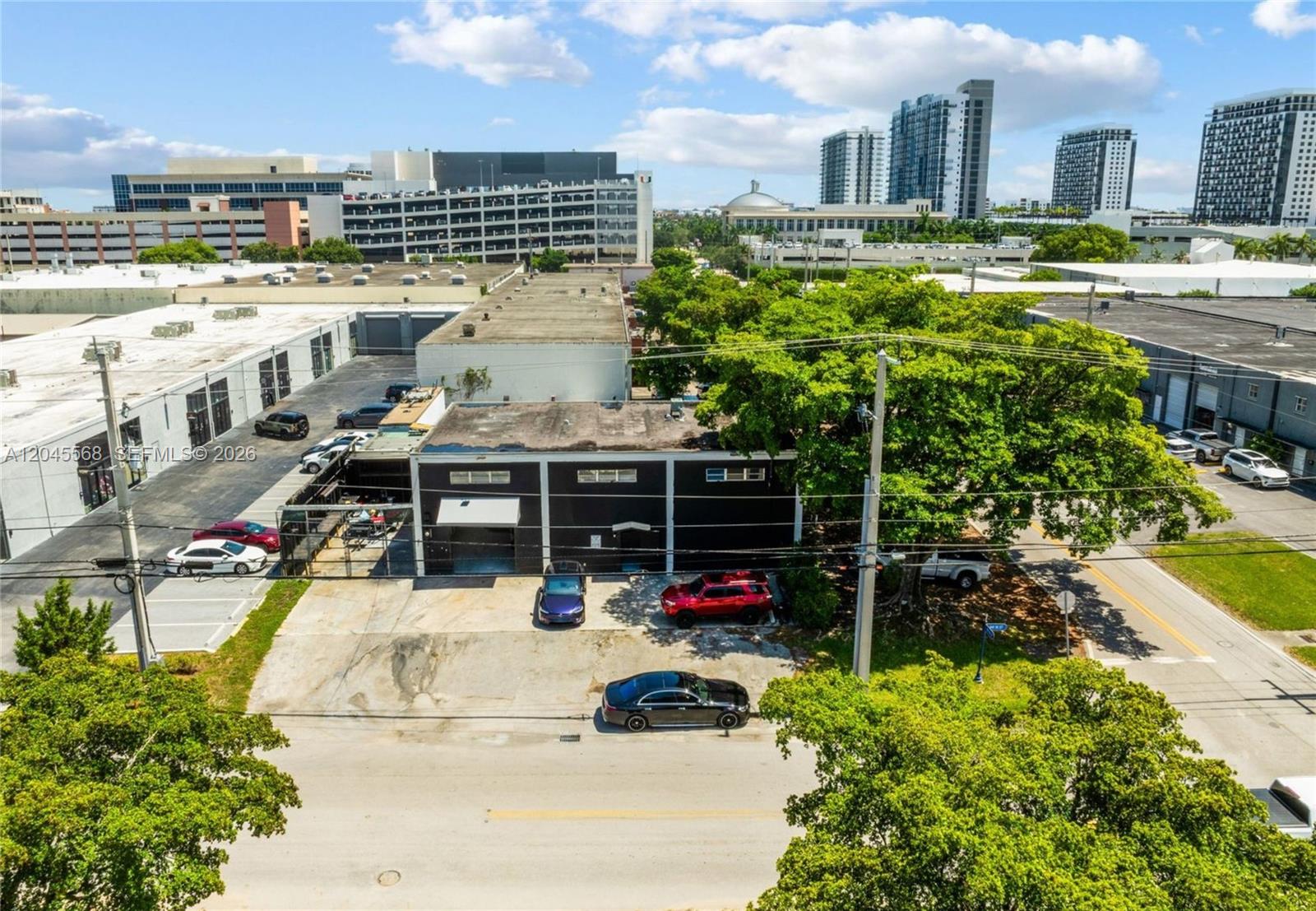 An aerial view shows a dark-colored industrial building with a parking lot and surrounding trees — 5571 NW 84th Ave, Doral FL 33166, DORAL, FL
