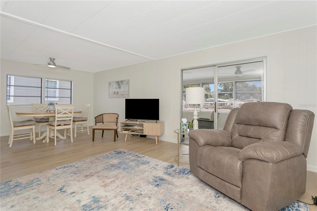 A living room features light wood flooring, a brown recliner, and an adjacent dining area — 115 WHITE OAK WAY, SARASOTA, FL