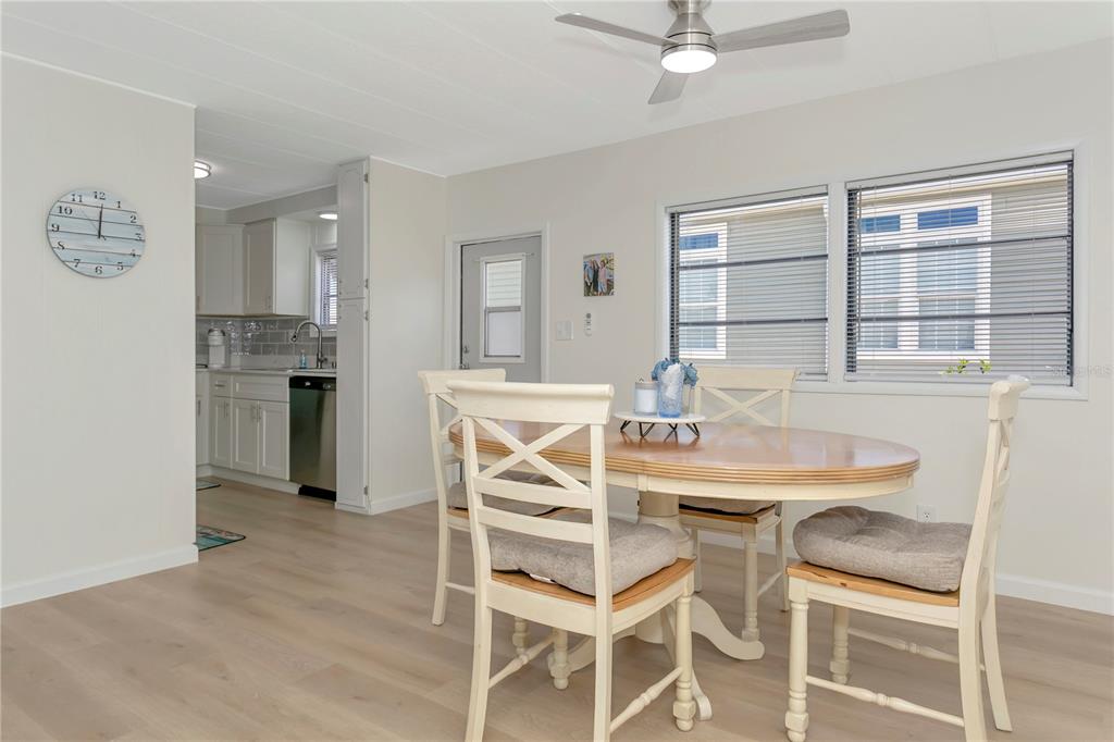 A dining area with a round table and chairs sits adjacent to a white kitchen — 115 WHITE OAK WAY, SARASOTA, FL