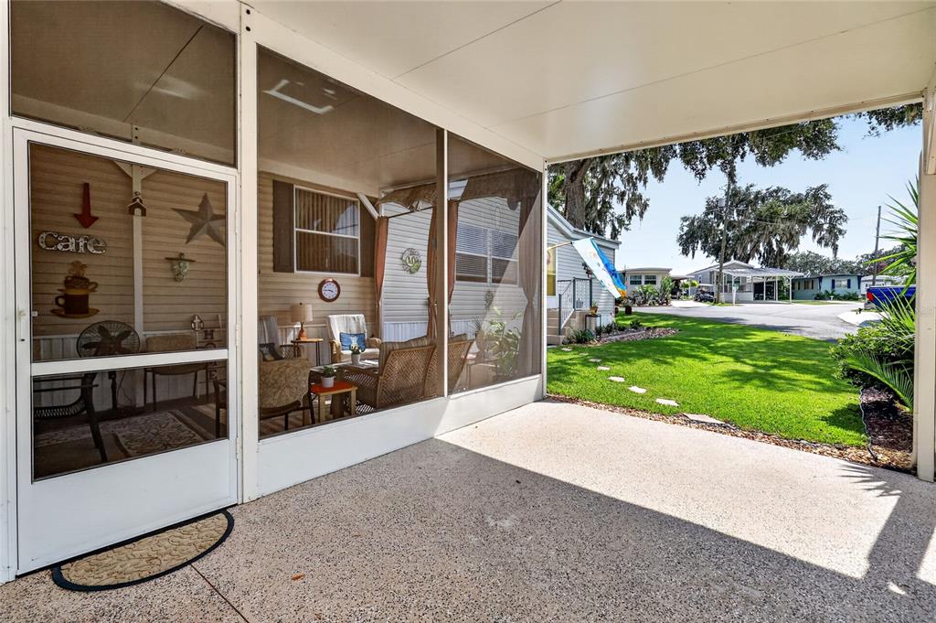 A screened-in porch with a concrete floor overlooks a grassy yard and neighborhood street — 704 KIMBERLY AVENUE, LEESBURG, FL