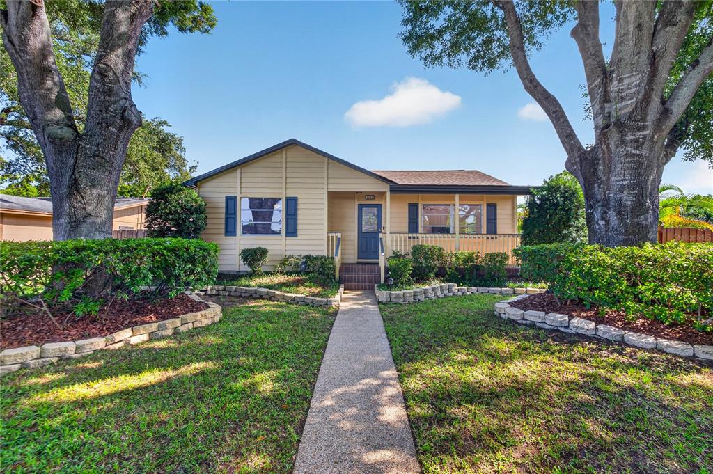 A single-story house with tan siding, a front porch, and mature trees in the yard — 6113 10TH AVENUE S, GULFPORT, FL