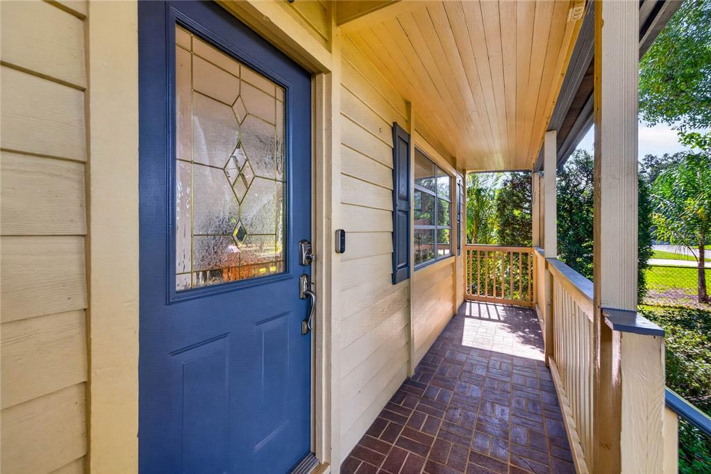A blue front door opens onto a covered porch with brick-patterned flooring and wooden railings — 6113 10TH AVENUE S, GULFPORT, FL