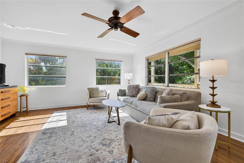 A living room features a gray sofa, two armchairs, a ceiling fan, and wood flooring — 6113 10TH AVENUE S, GULFPORT, FL