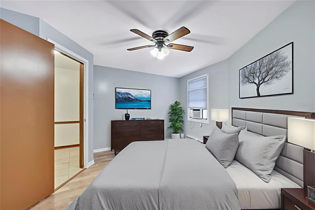 A bedroom features a bed with a gray headboard, a dresser, and a ceiling fan — 7830 BUTLER AVENUE, HUDSON, FL