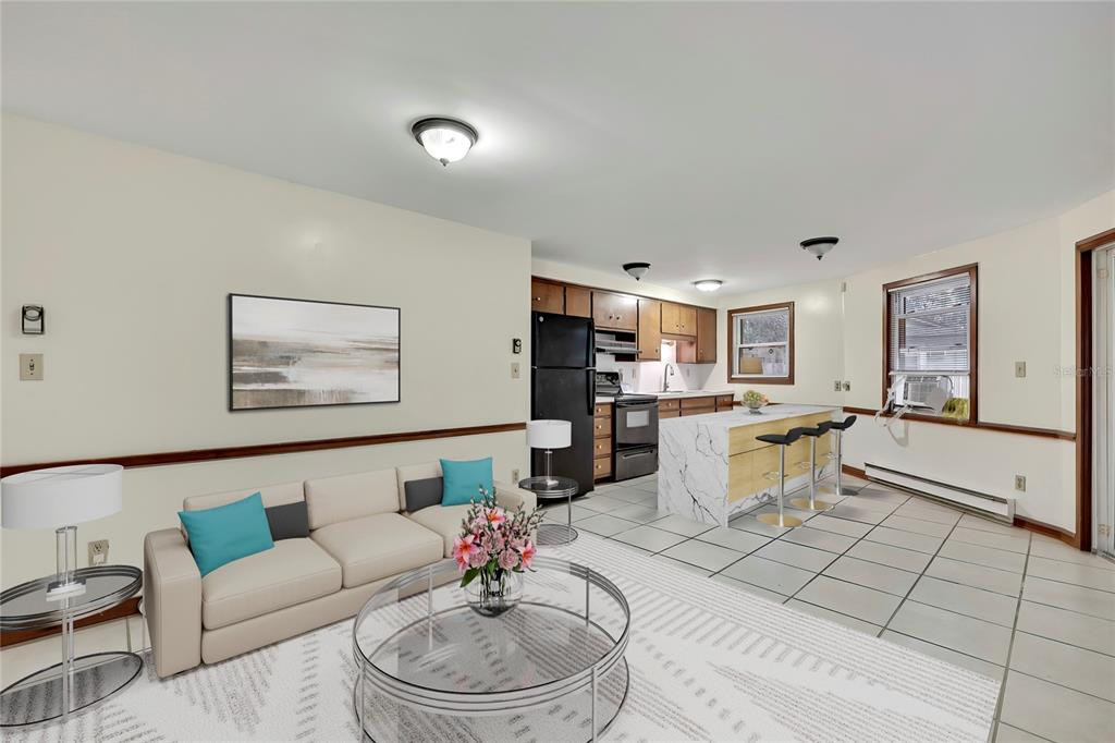 An open-concept living room and kitchen featuring a sofa, coffee table, and marble-topped island — 7830 BUTLER AVENUE, HUDSON, FL