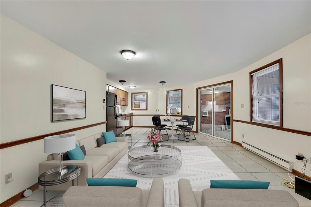 A living room and kitchen open-concept space with tile flooring, neutral walls, and sliding doors — 7830 BUTLER AVENUE, HUDSON, FL