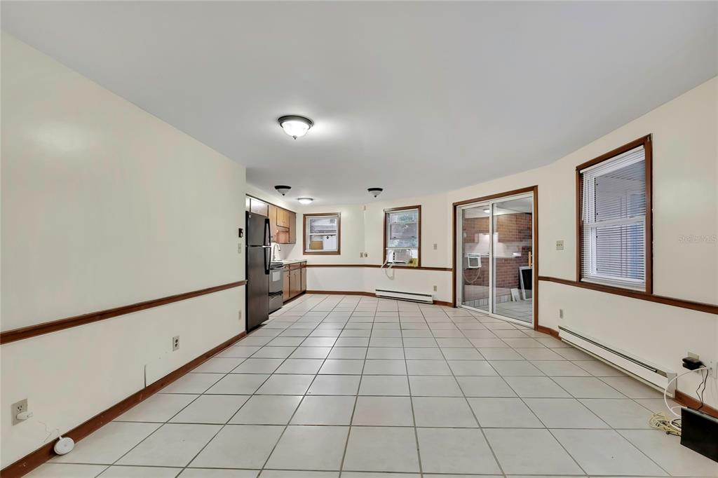 A kitchen and dining area with white tile floors, beige walls, and a sliding glass door — 7830 BUTLER AVENUE, HUDSON, FL