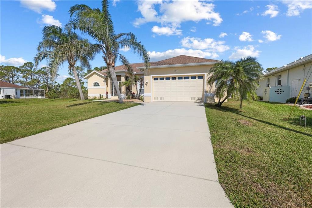 A single-story house with a two-car garage, palm trees, and a concrete driveway — 127 WHITE MARSH LANE, ROTONDA WEST, FL