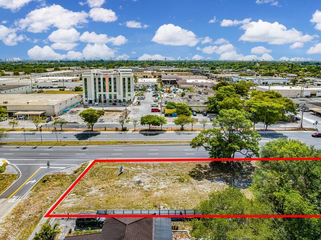 An aerial view shows a vacant, fenced-in rectangular lot adjacent to a multi-lane road — NW 27th, Opa-Locka FL 33054, OPA-LOCKA, FL