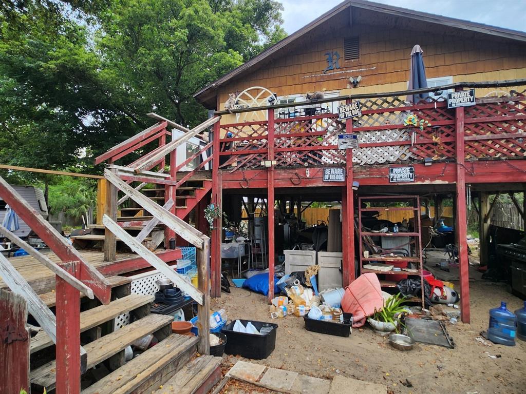 An elevated wooden deck with red railings overlooks a cluttered area beneath the house — 33702 VERDA AVENUE, LEESBURG, FL