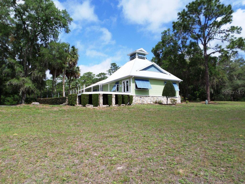 A light green house with a metal roof and a cupola sits on a lawn — 8621 SW 200TH CIR, DUNNELLON, FL
