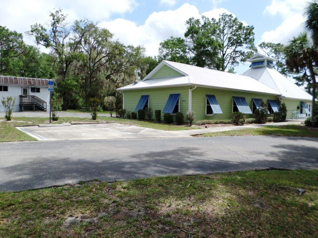 A light green building with a metal roof and blue shutters sits near a parking lot — 8621 SW 200TH CIR, DUNNELLON, FL