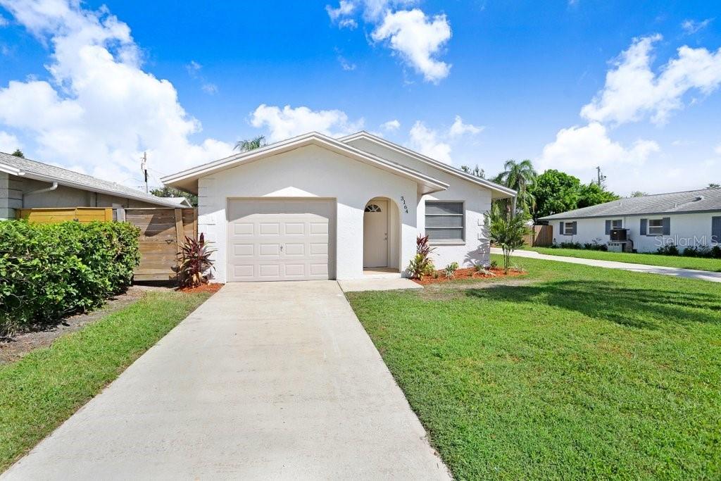 A single-story white house with a concrete driveway, a garage, and a front lawn — 3166 DOWNING STREET, CLEARWATER, FL