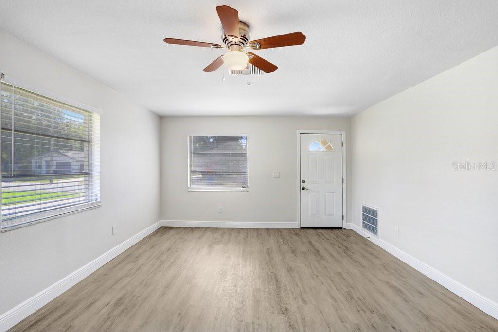 A room with light-colored walls, wood-look flooring, a ceiling fan, and two windows — 3166 DOWNING STREET, CLEARWATER, FL