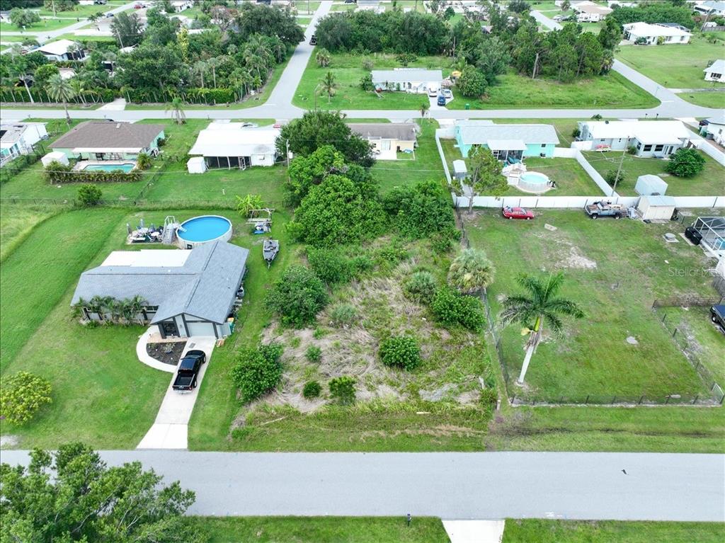 An aerial view shows a vacant lot situated between two residential houses with swimming pools — 3268 PINETREE STREET, PORT CHARLOTTE, FL