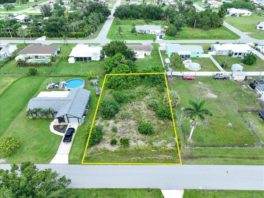 An aerial view shows a vacant, rectangular residential lot outlined in yellow between two houses — 3268 PINETREE STREET, PORT CHARLOTTE, FL