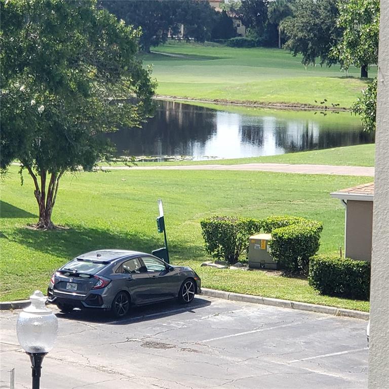 A gray hatchback is parked in a lot overlooking a pond and golf course — 7300 WESTPOINTE BOULEVARD UNIT 732, ORLANDO, FL