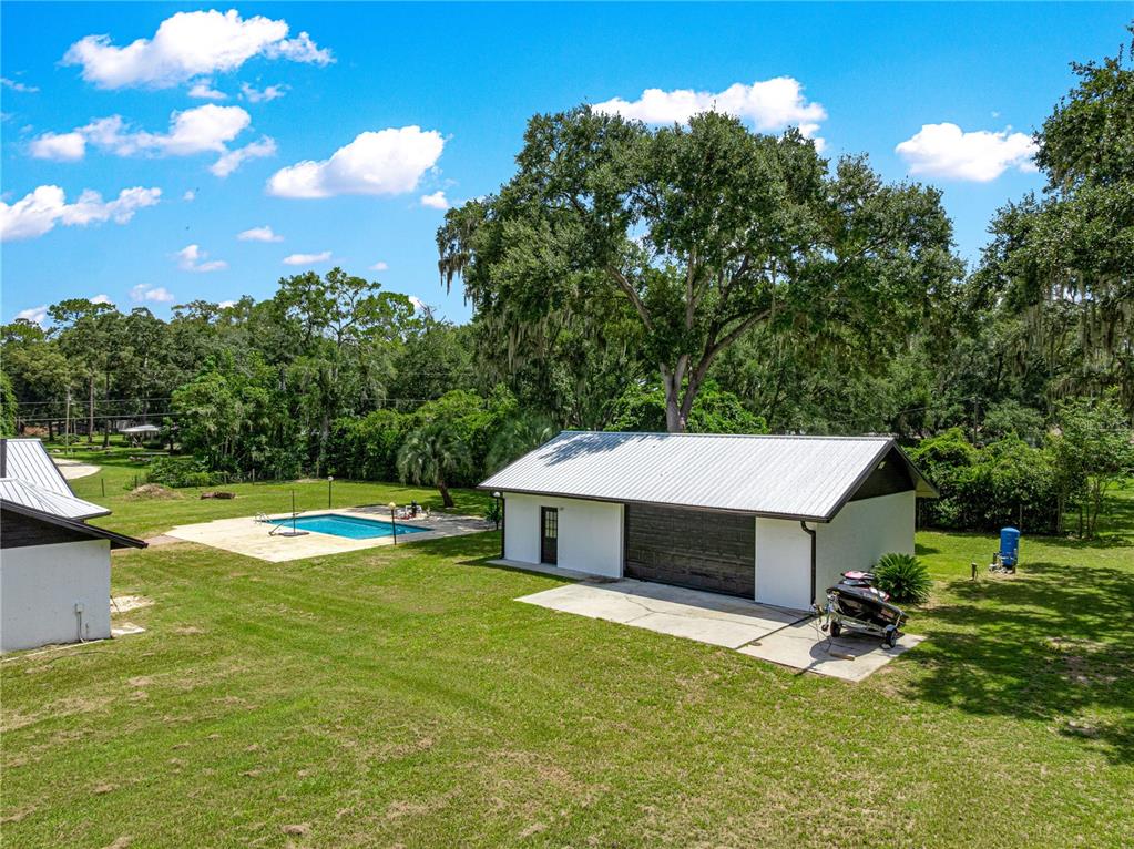 An aerial view shows a detached garage, a swimming pool, and trees on a grassy lot — 6575 NW 50TH AVENUE, OCALA, FL