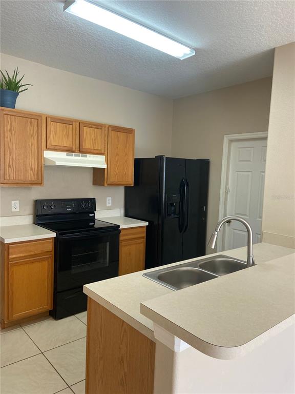 A kitchen features oak cabinets, black appliances, a double-basin sink, and a light-colored countertop — 628 MADINA CIRCLE, DAVENPORT, FL