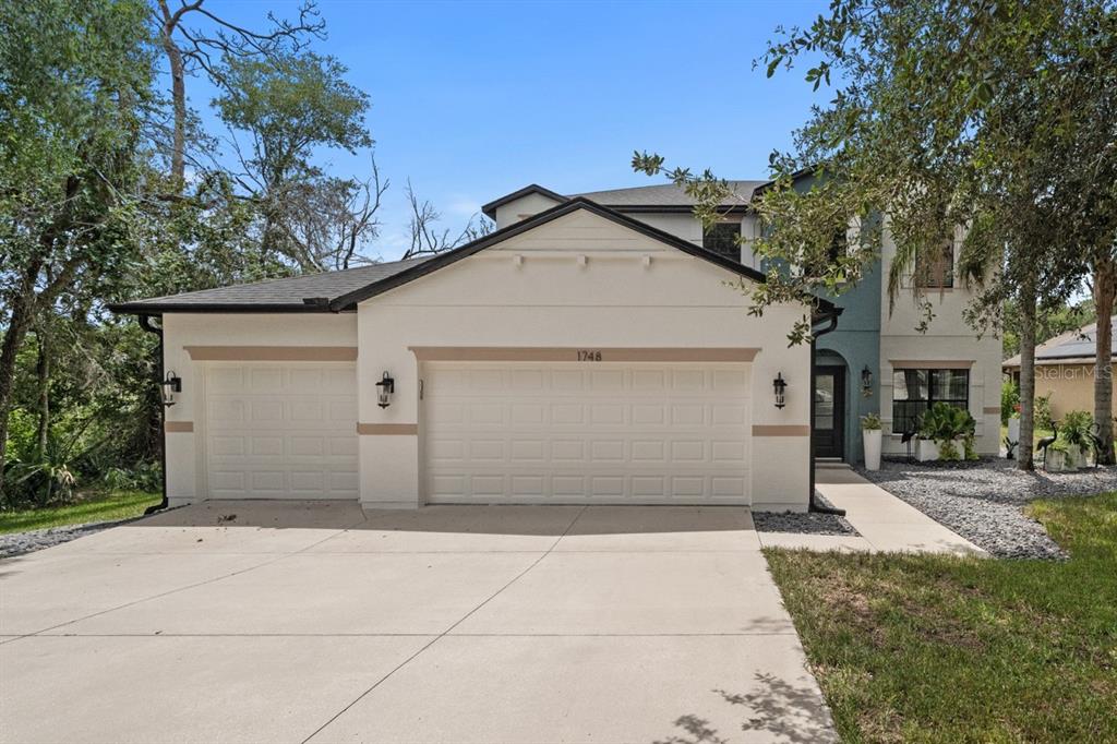 A two-story house with a three-car garage and a concrete driveway under a blue sky — 1748 WATERSIDE OAKS DRIVE, ORANGE CITY, FL
