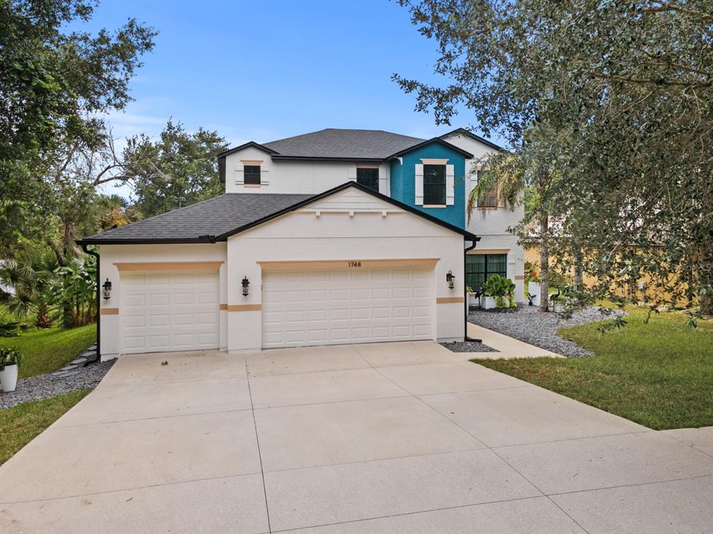 A two-story house with a three-car garage, white stucco exterior, and a blue accent wall — 1748 WATERSIDE OAKS DRIVE, ORANGE CITY, FL