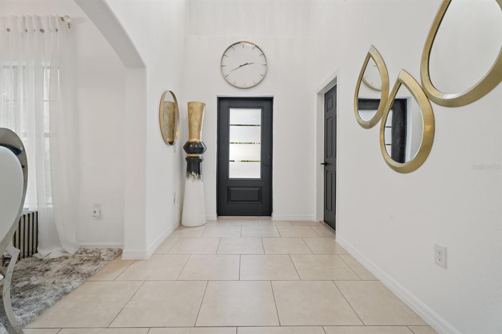 A bright entryway features white walls, tiled flooring, a black front door, and decorative mirrors — 1748 WATERSIDE OAKS DRIVE, ORANGE CITY, FL