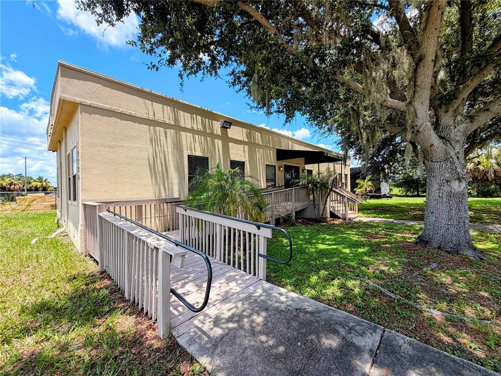 A tan commercial building features a wooden wheelchair ramp leading to an entrance under trees — 2290 E 92 HIGHWAY, PLANT CITY, FL