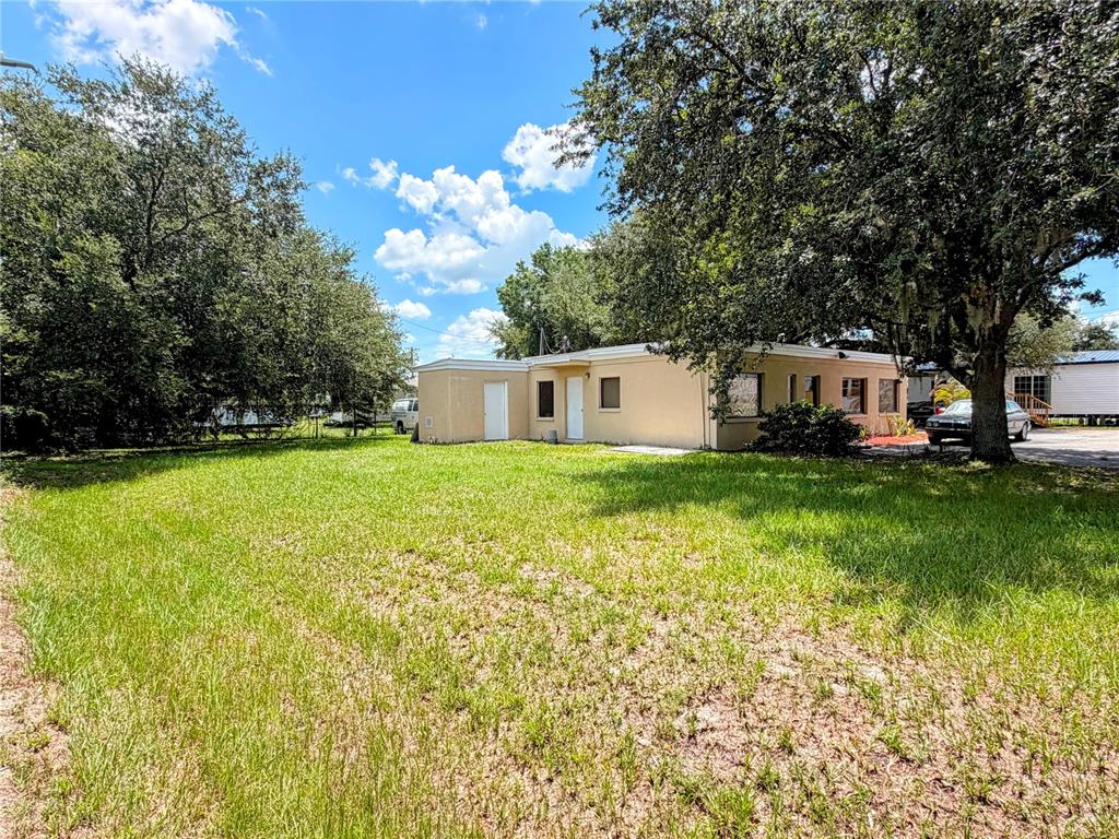 A single-story tan building sits on a grassy lot surrounded by large trees — 2290 E 92 HIGHWAY, PLANT CITY, FL
