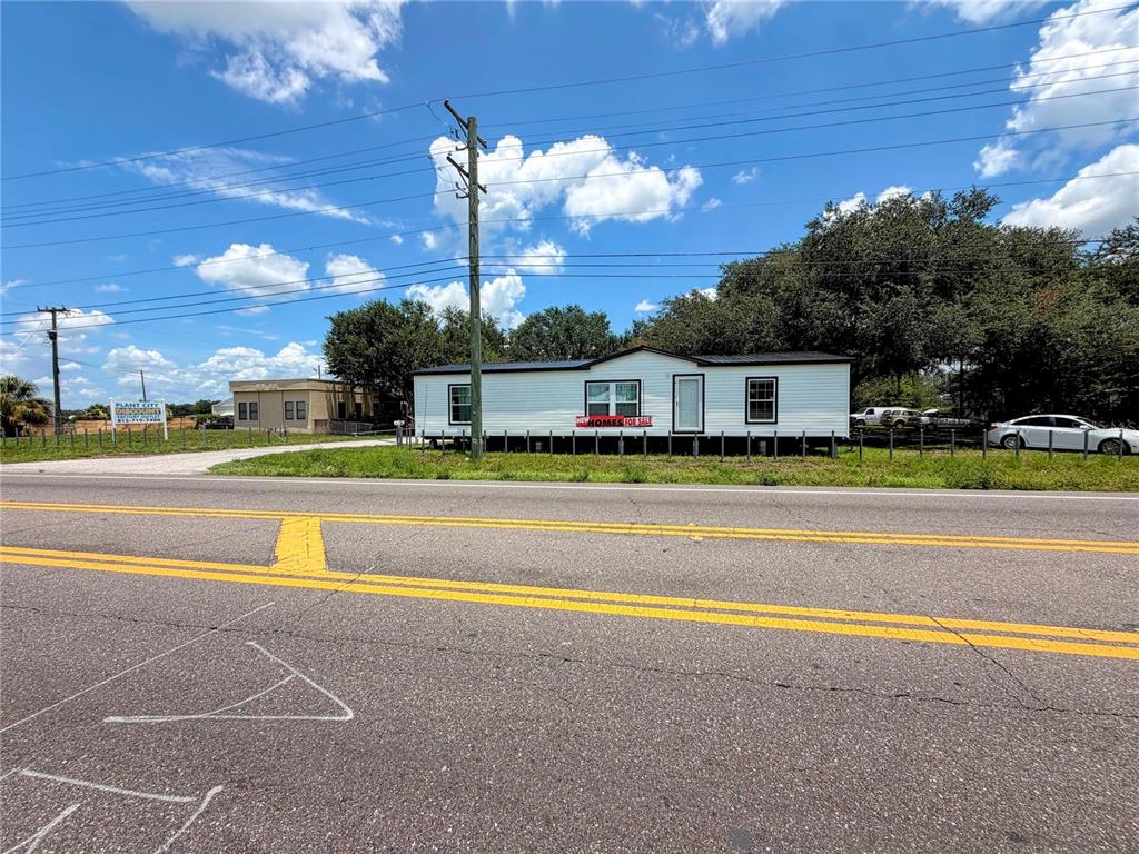 A white manufactured home sits on a lot next to a road under a cloudy sky — 2290 E 92 HIGHWAY, PLANT CITY, FL