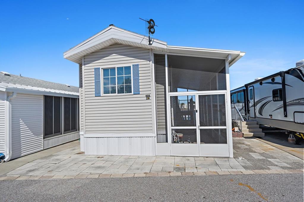 A light-colored mobile home with a screened-in porch and a paved patio area — 108 BAHIA DRIVE, PALMETTO, FL