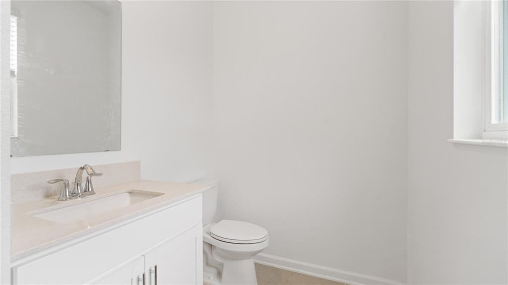 A bathroom with a white vanity, a mirror, a toilet, and a window — 2204 RED SUN STREET, APOPKA, FL