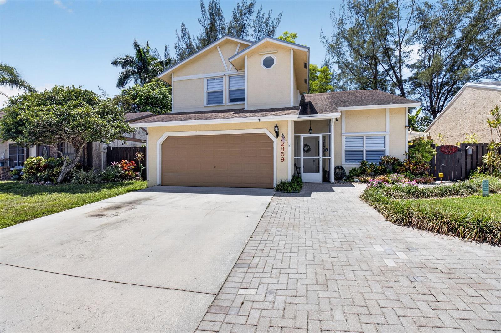 A two-story house with a beige exterior, a brown garage door, and a paved driveway — 22859 N Sandalfoot Boulevard, Boca Raton FL 33428, BOCA RATON, FL