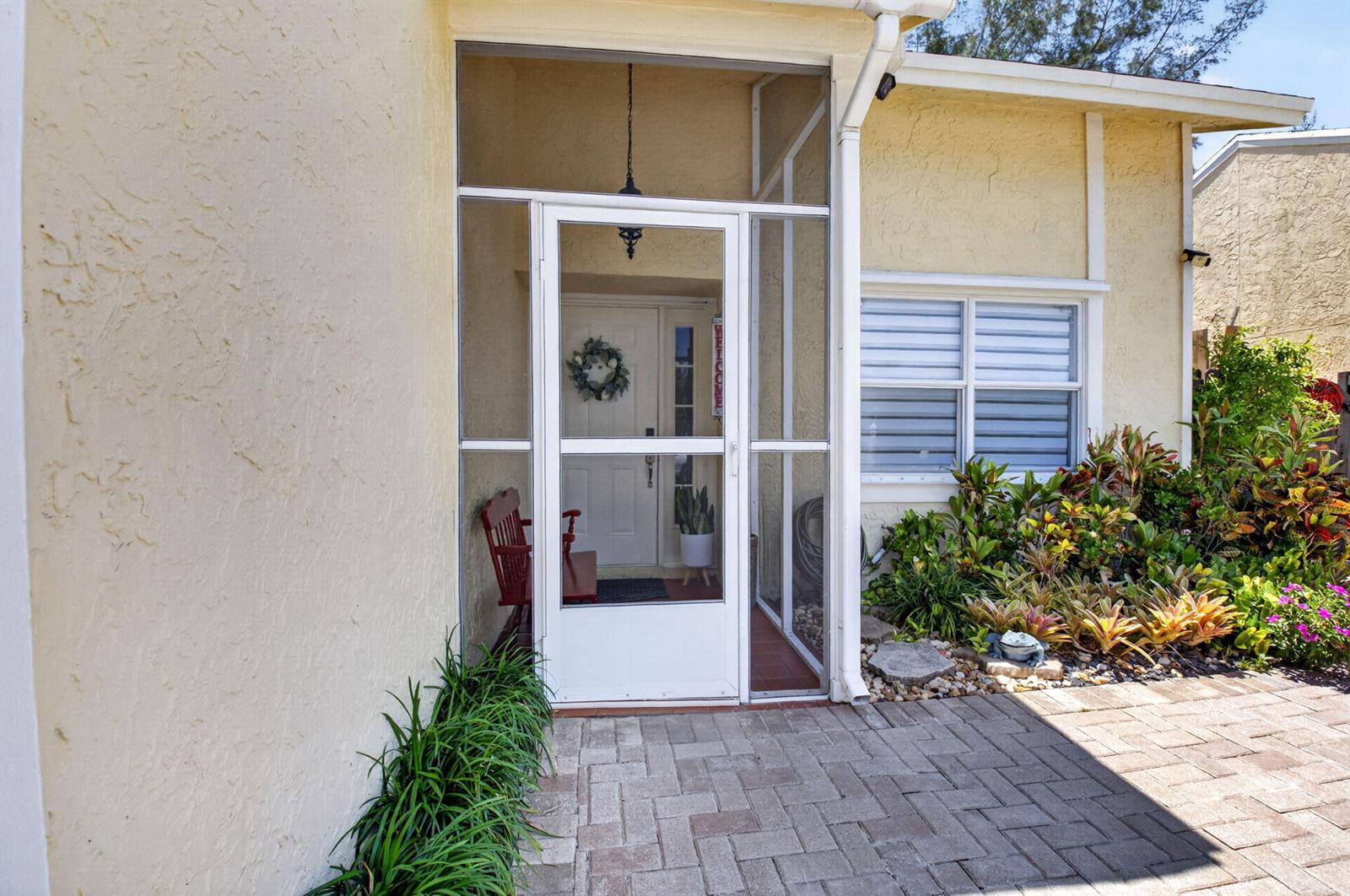The exterior view shows a screened-in front entryway with a paver patio and landscaping — 22859 N Sandalfoot Boulevard, Boca Raton FL 33428, BOCA RATON, FL