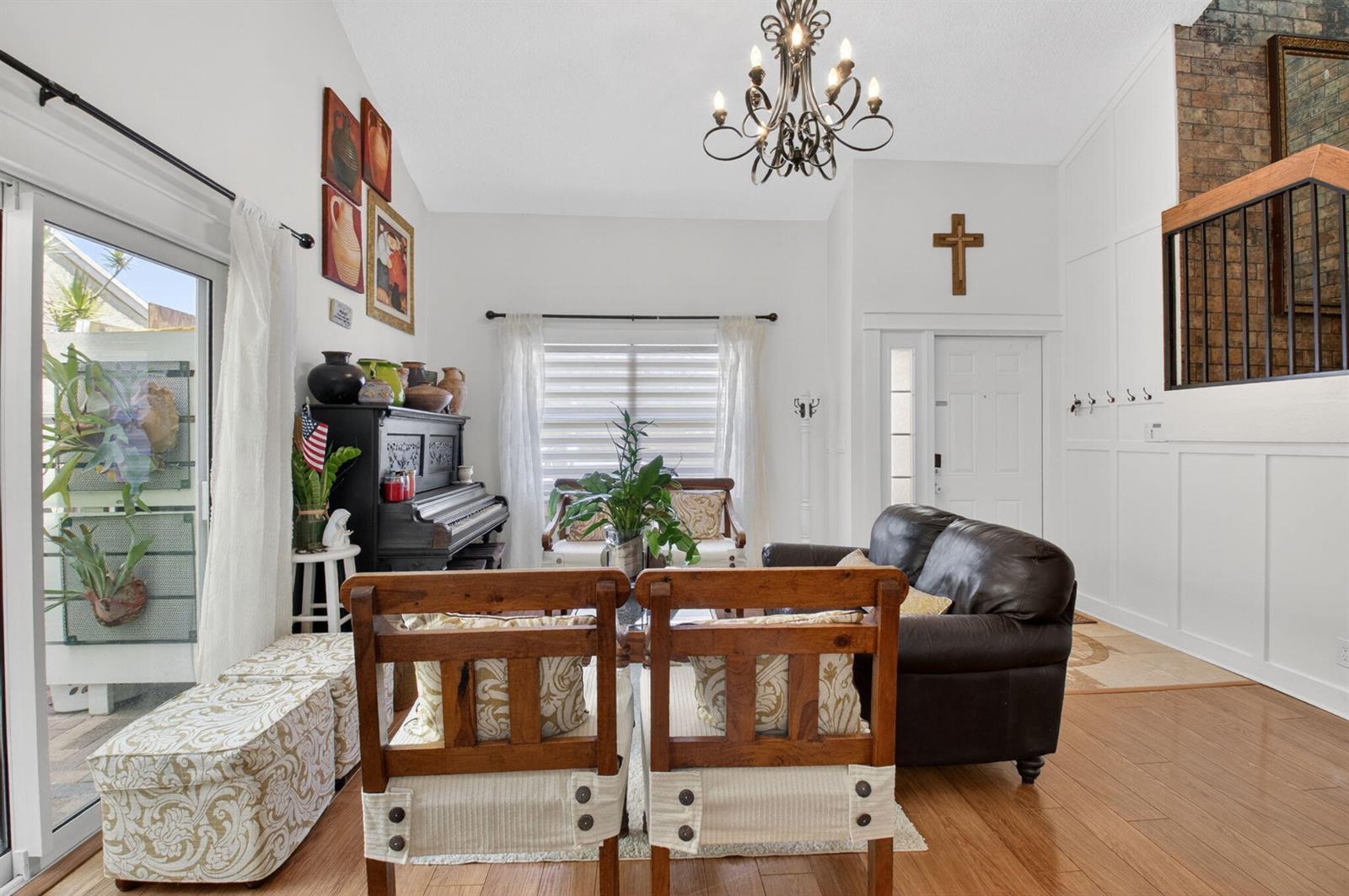 A living room features a piano, leather sofa, wooden chairs, and a chandelier — 22859 N Sandalfoot Boulevard, Boca Raton FL 33428, BOCA RATON, FL
