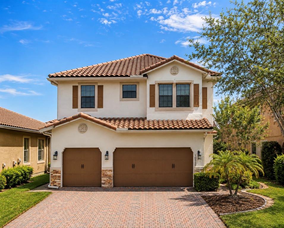 A two-story house with a tiled roof, stucco exterior, and a three-car garage — 10359 HENBURY STREET, ORLANDO, FL