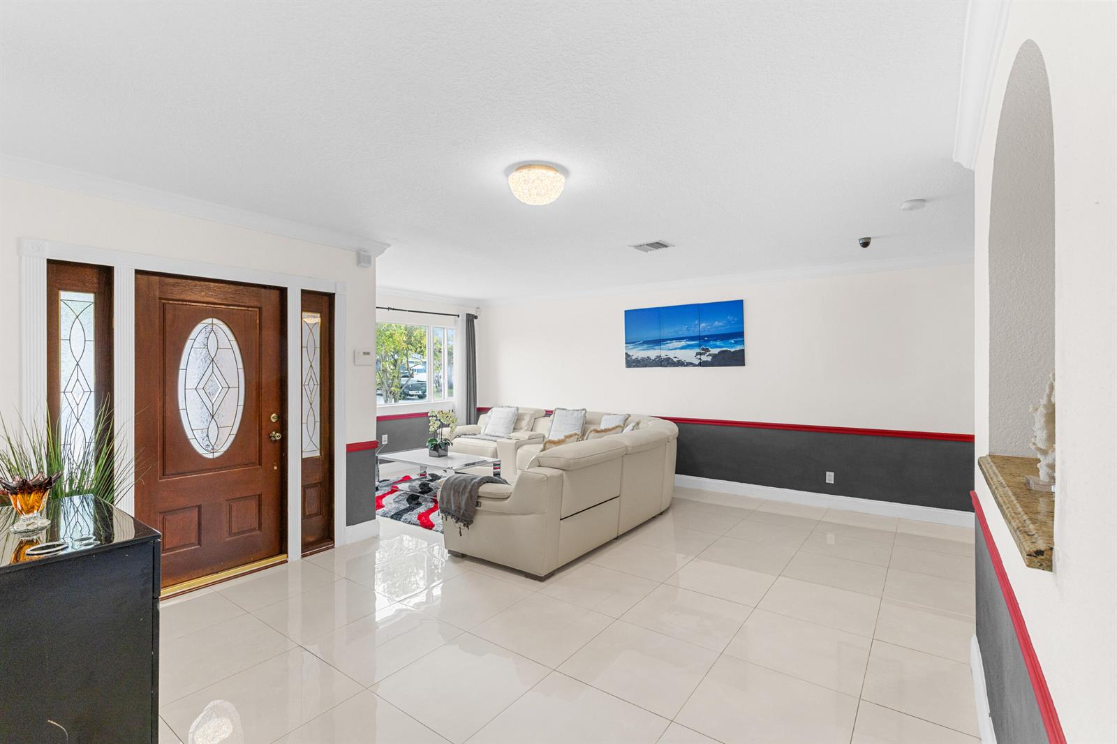 A living room features white tile floors, a beige sectional sofa, and dark gray wainscoting — 321 N 72nd Terrace, Hollywood FL 33024, HOLLYWOOD, FL