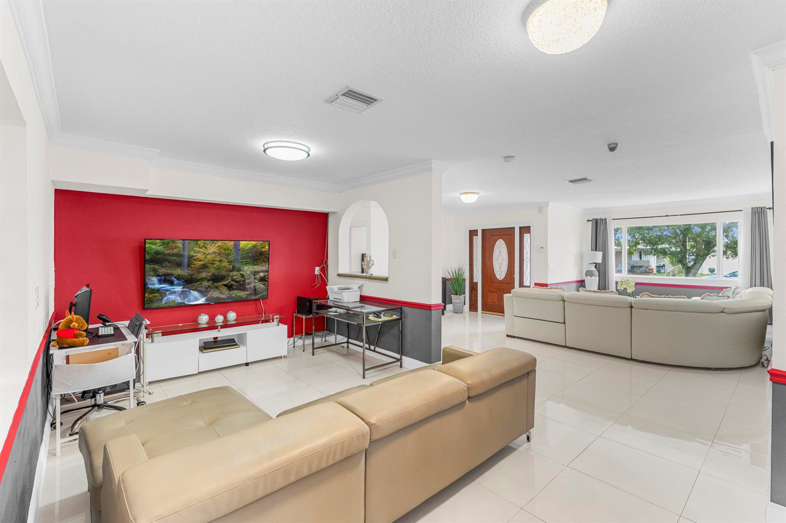 A living room features a red accent wall, a television, and two beige sectional sofas — 321 N 72nd Terrace, Hollywood FL 33024, HOLLYWOOD, FL