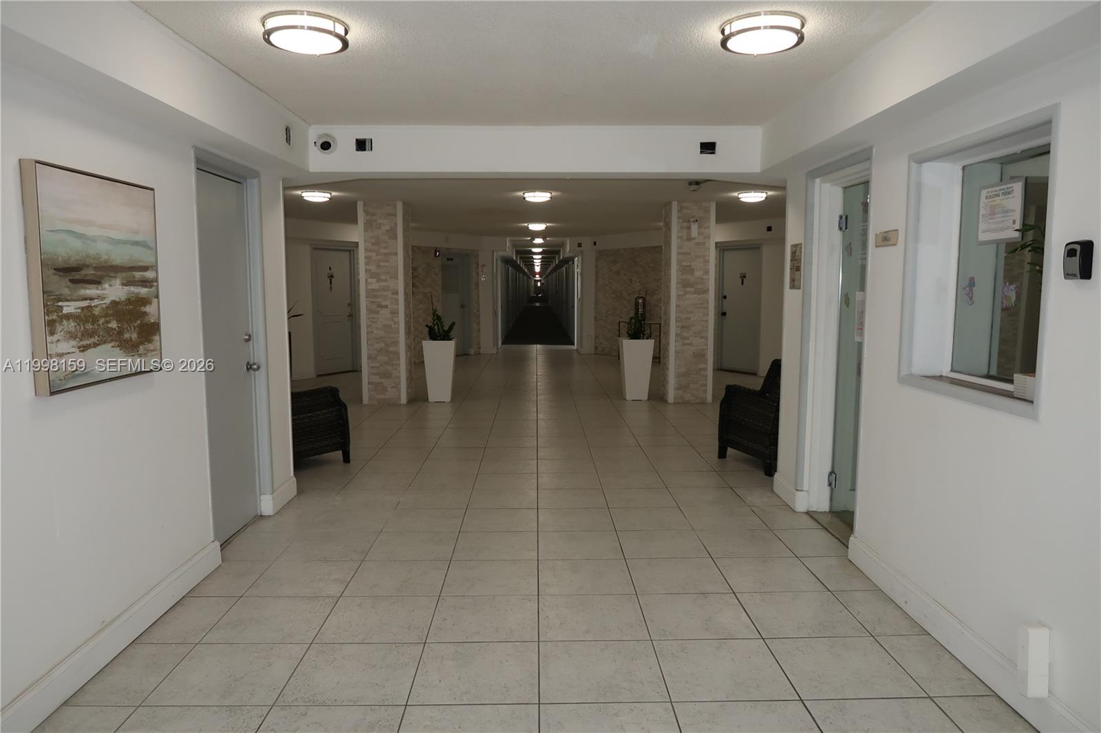 A tiled hallway features white walls, recessed lighting, and two dark chairs by stone pillars — 1913 S Ocean Dr # 300, Hallandale Beach FL 33009, HALLANDALE BEACH, FL