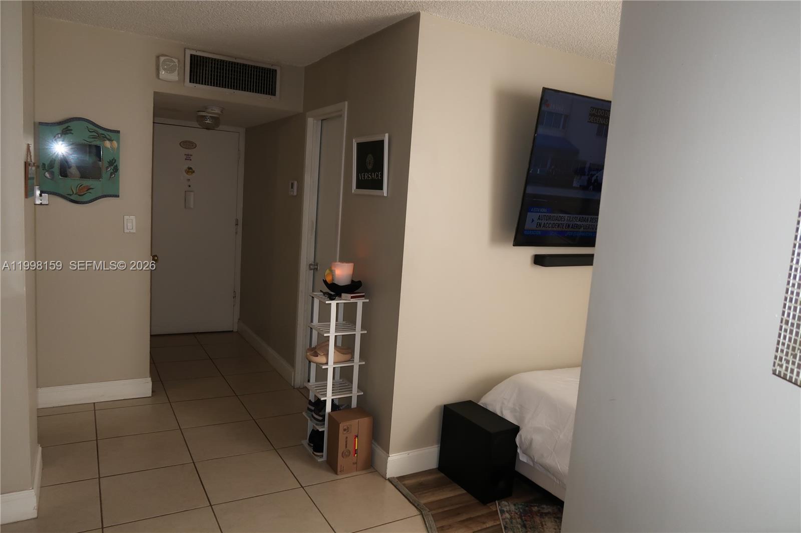 A tiled entryway leads to a bedroom area with a wall-mounted television and bed — 1913 S Ocean Dr # 300, Hallandale Beach FL 33009, HALLANDALE BEACH, FL