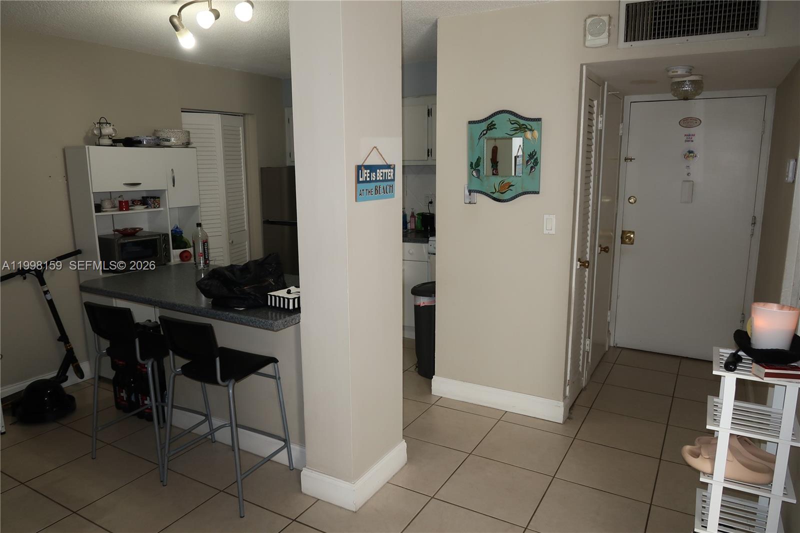 A kitchen with a breakfast bar, stools, and an adjacent entryway with tiled floors — 1913 S Ocean Dr # 300, Hallandale Beach FL 33009, HALLANDALE BEACH, FL