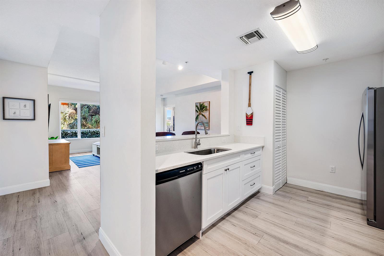 A kitchen features white cabinets, stainless steel appliances, and light wood-look flooring — 1203 Town Center Drive # 201, Jupiter FL 33458, JUPITER, FL