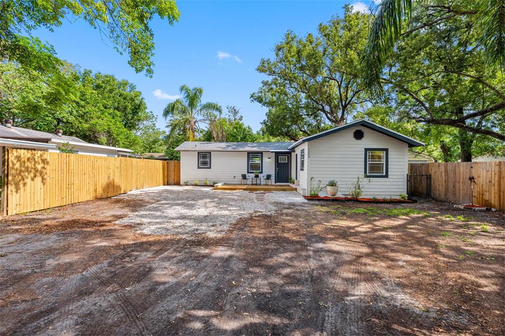 A single-story house with light siding, a gravel driveway, and a wooden fence — 1208 E CHILKOOT AVENUE, TAMPA, FL