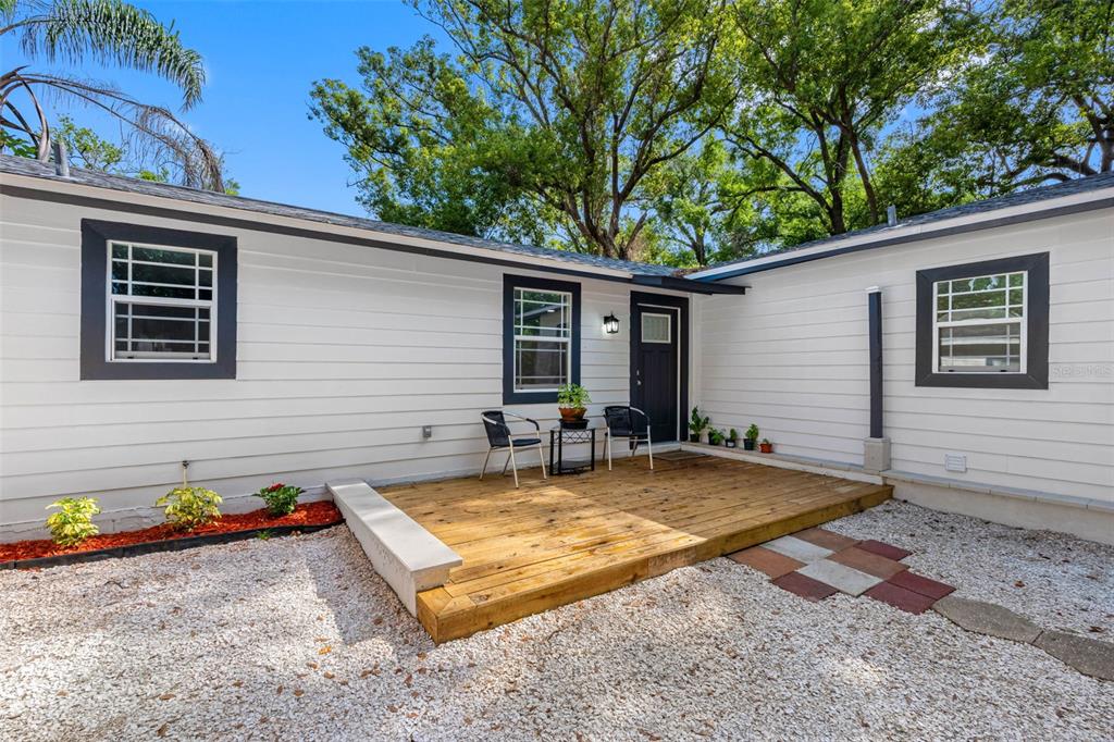 A white house exterior features a wooden deck, two chairs, and a small table — 1208 E CHILKOOT AVENUE, TAMPA, FL