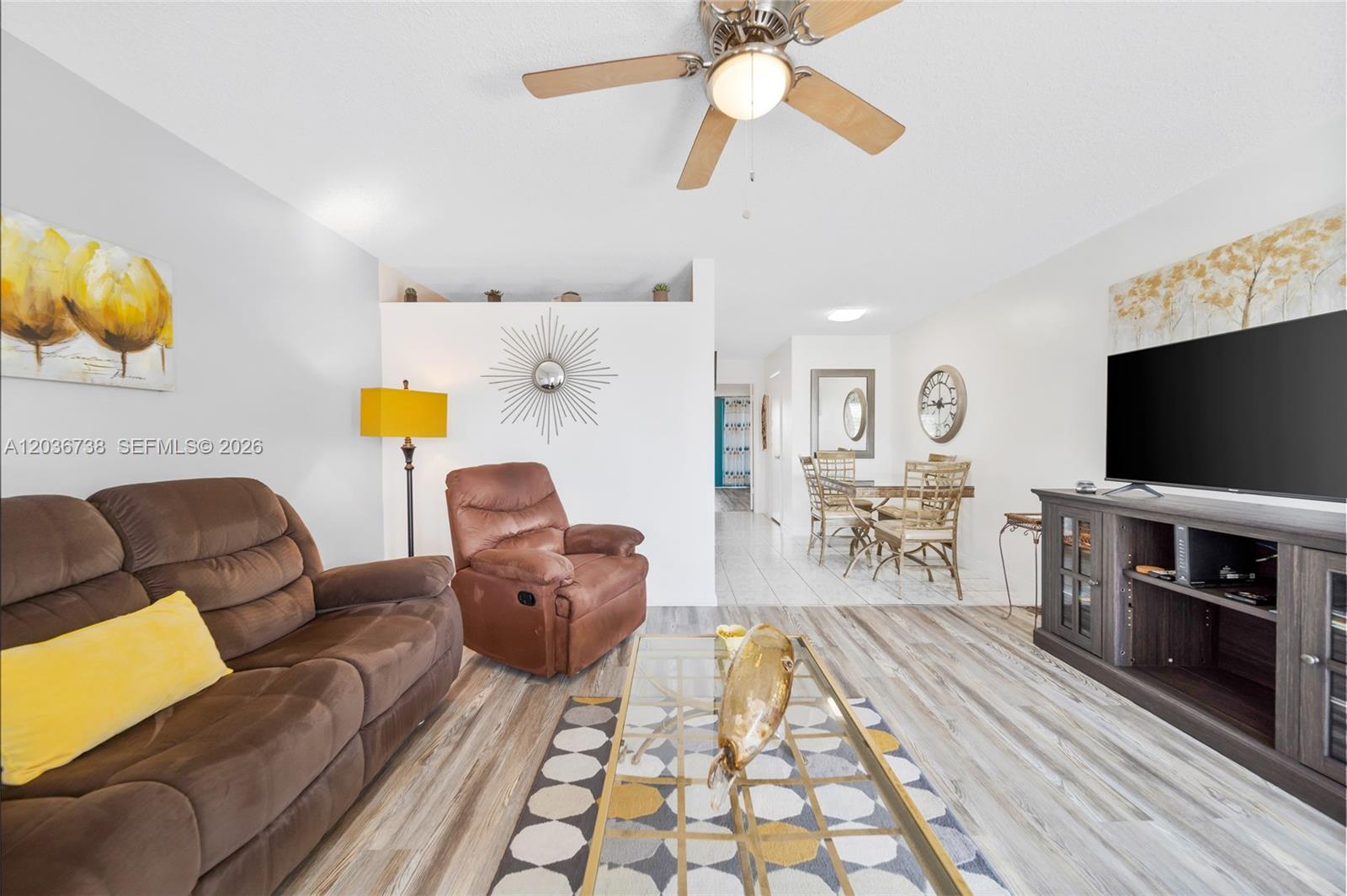 A living room features a brown sofa, recliner, glass coffee table, and a television console — 15610 NE 6th Ave # 34C, Miami FL 33162, MIAMI, FL